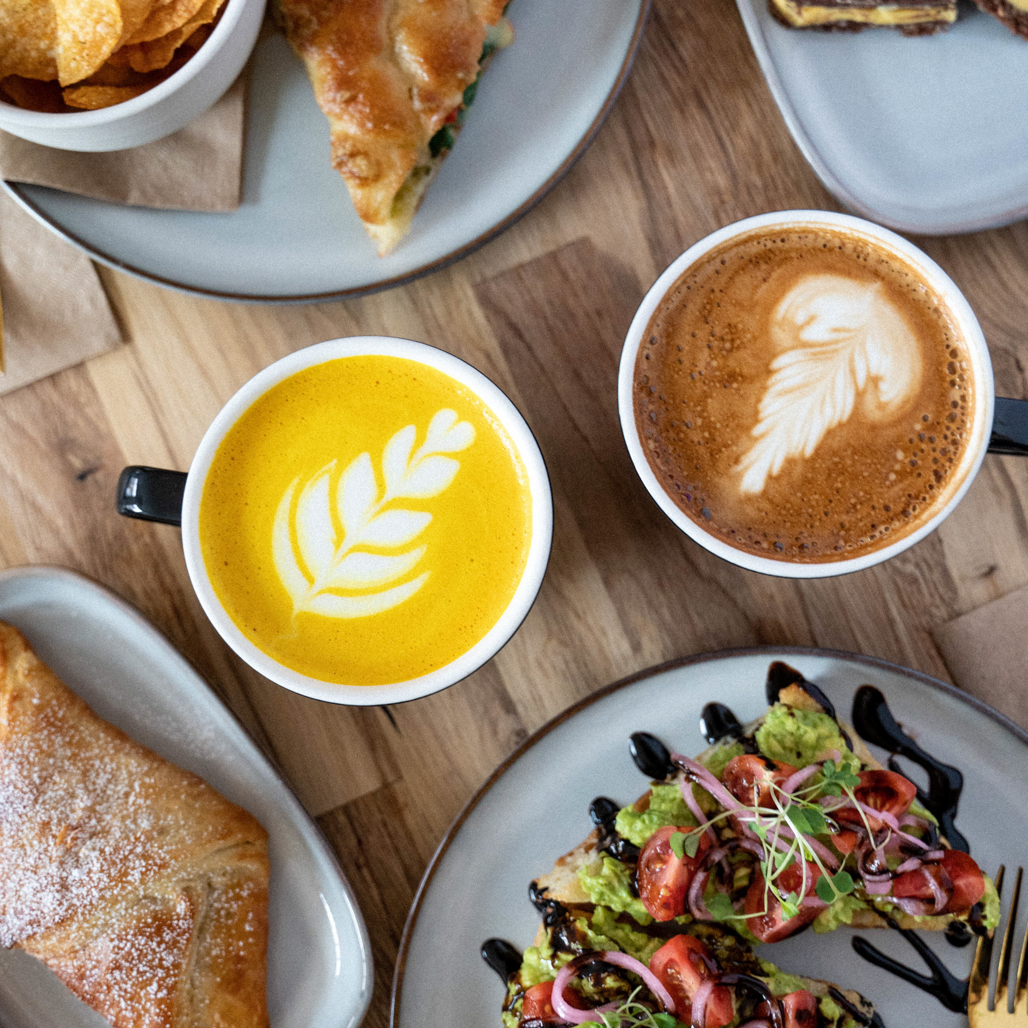 Lattes and delcious food set out on a rustic table