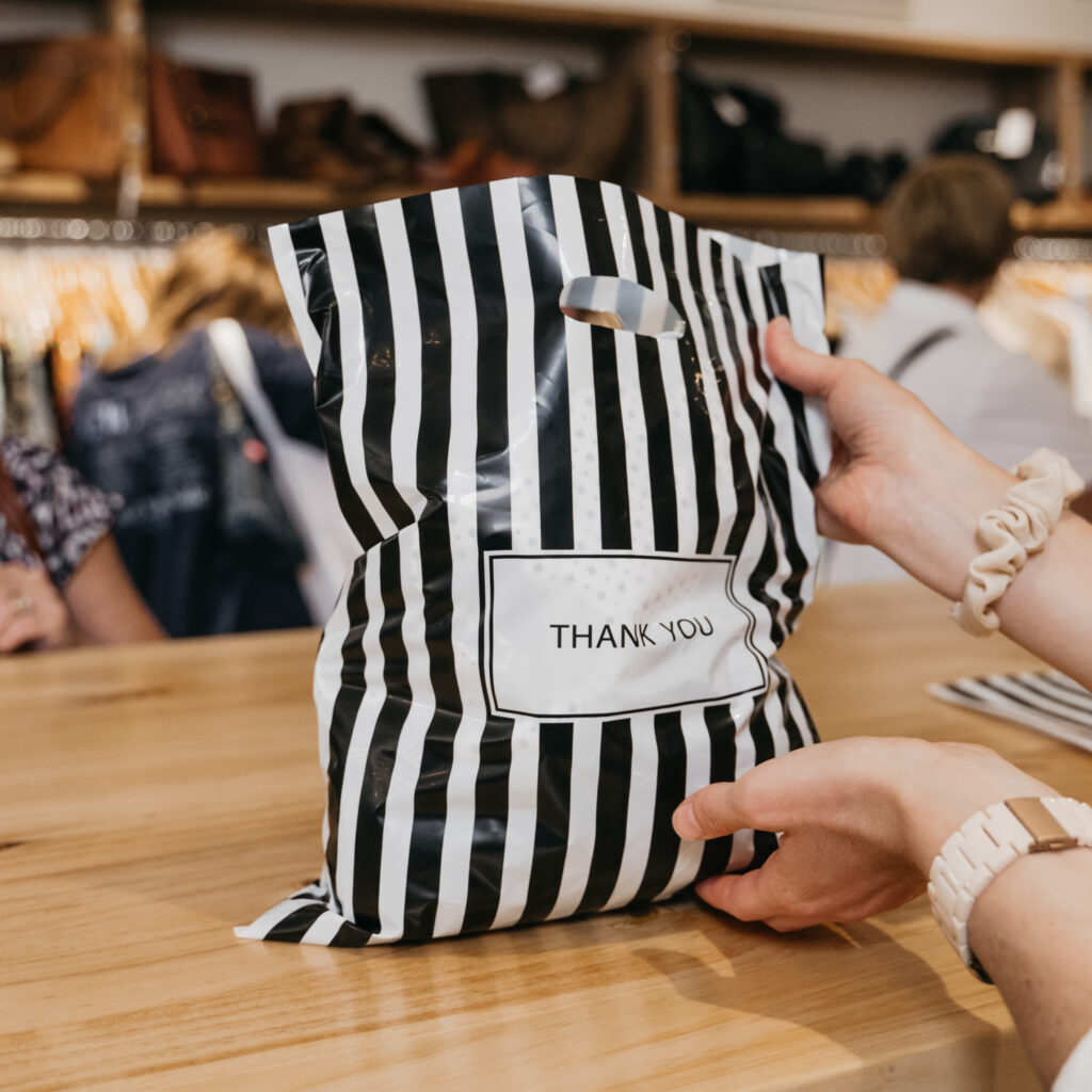 Shopping bag being handed over at Coastal Consignment
