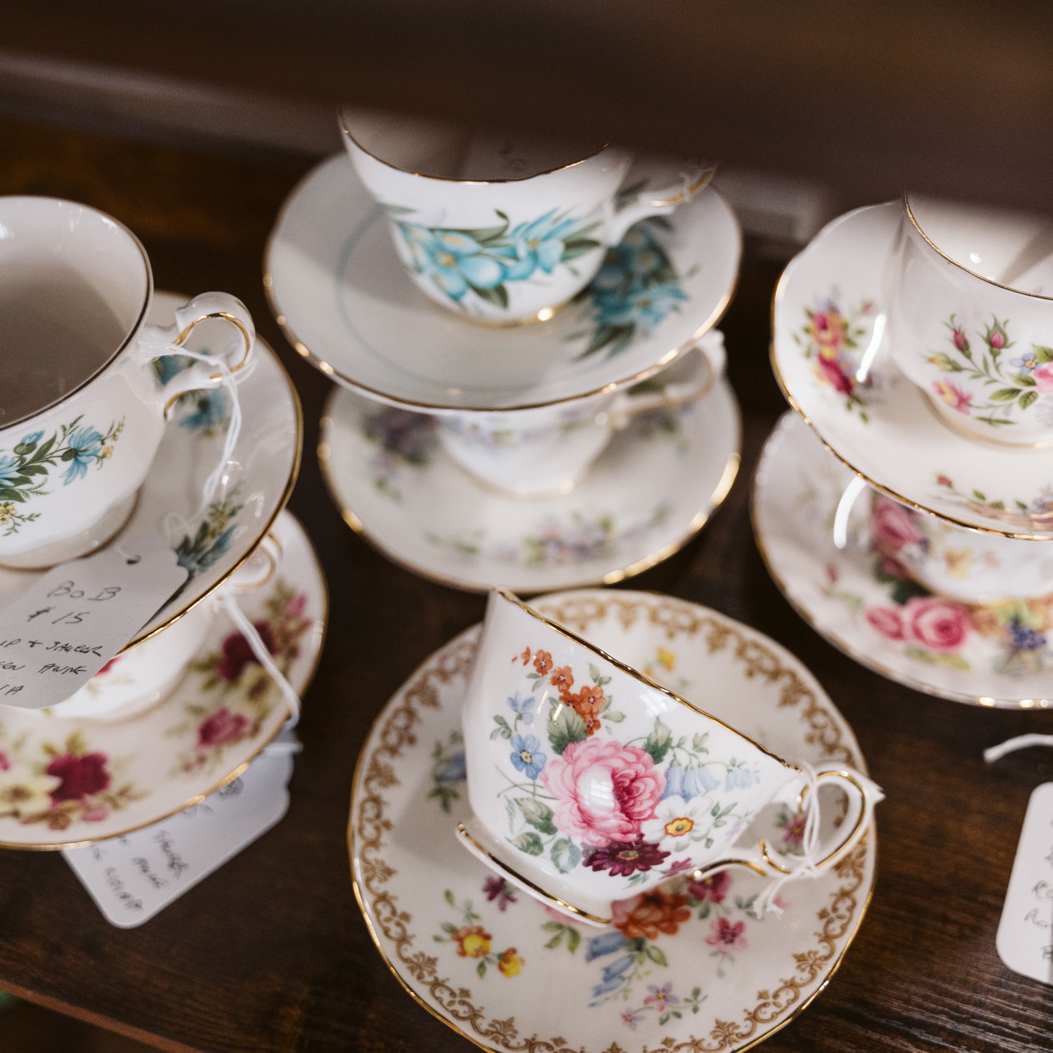Vintage Tea Cups stacked on a shelf with floral motif and gold trim