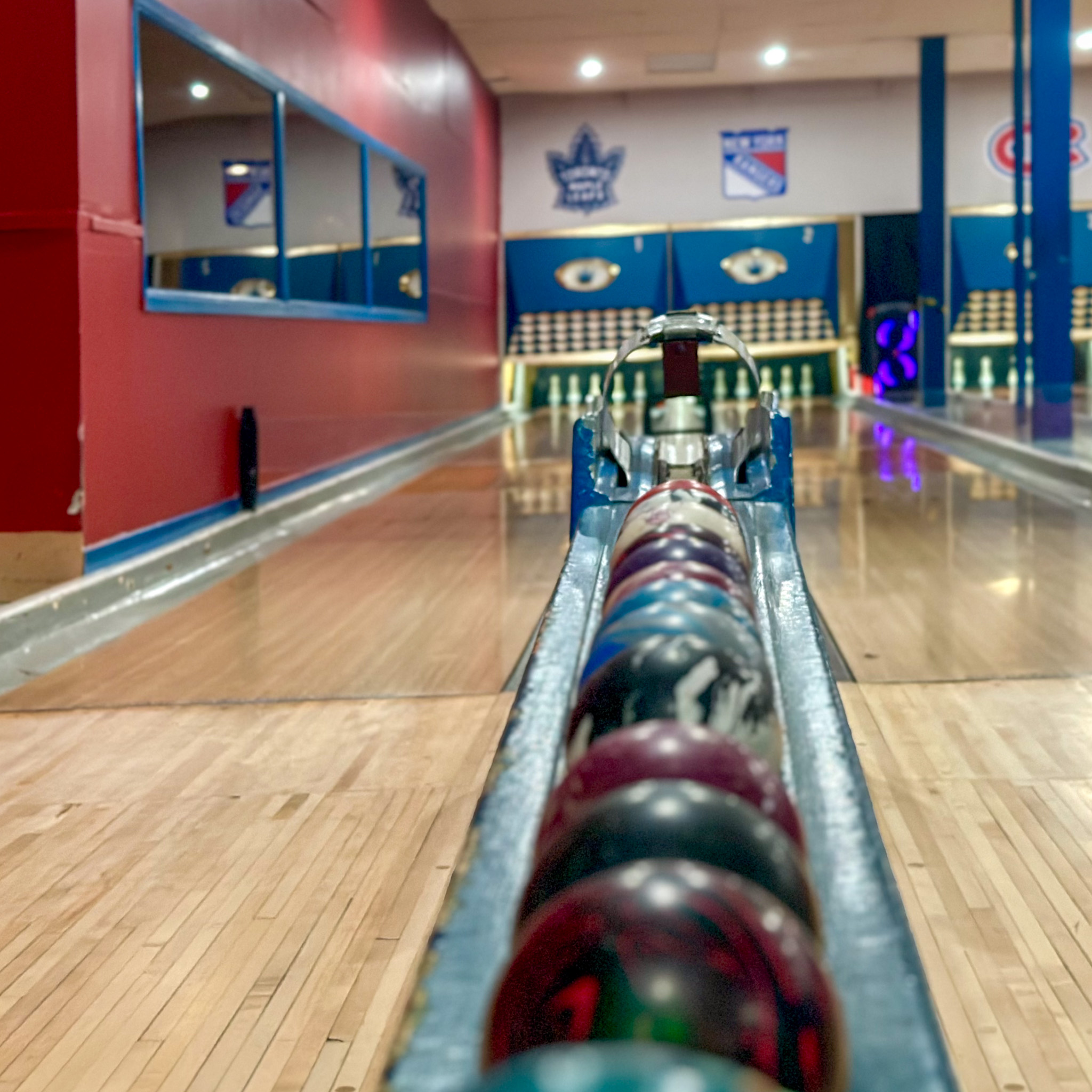 A low angle view of the 5 pin bowling balls and down the lane to the pins
