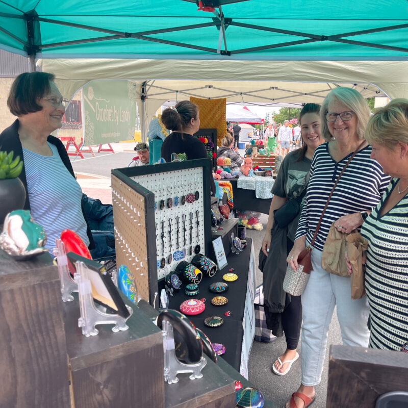 Attendees browse jewllery in a vendor tent at Bridge Street Summerfest